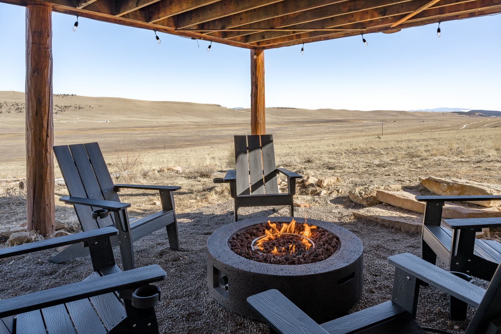 Fire pit burning with five Adirondack chairs under the deck